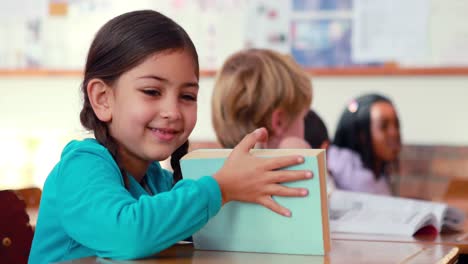 Süße-Schülerin-Lächelt-In-Die-Kamera-An-Ihrem-Schreibtisch-Im-Klassenzimmer
