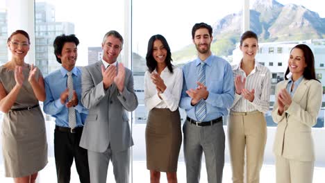 Business-team-standing-in-a-row-clapping-at-camera