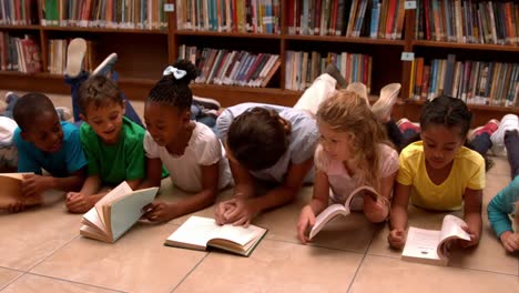 Teacher-and-pupils-reading-books-on-library-floor