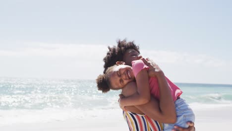 Smiling-african-american-mother-with-daughter-embracing-on-sunny-beach