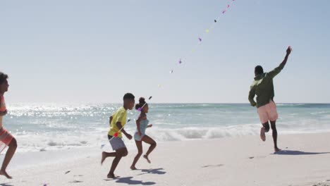 Lächelnde-Afroamerikanische-Familie,-Die-Am-Sonnigen-Strand-Drachen-Läuft-Und-Steigen-Lässt