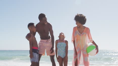 Portrait-of-smiling-african-american-family-embracing-on-sunny-beach