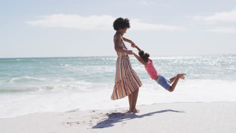 Lächelnde-Afroamerikanische-Mutter-Mit-Tochter,-Die-Am-Sonnigen-Strand-Spielt