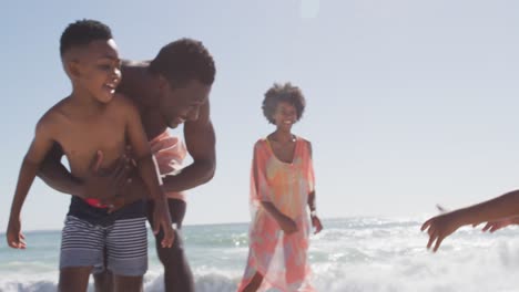 Lächelnde-Afroamerikanische-Familie,-Die-Am-Sonnigen-Strand-Mit-Ball-Spielt