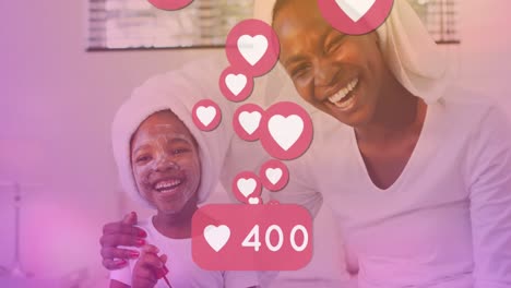 Animation-of-heart-reactions-over-happy-african-american-mother-and-daughter-during-skin-care