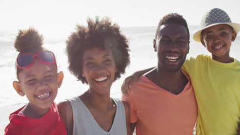 Porträt-Einer-Lächelnden-Afroamerikanischen-Familie,-Die-Sich-Am-Sonnigen-Strand-Umarmt