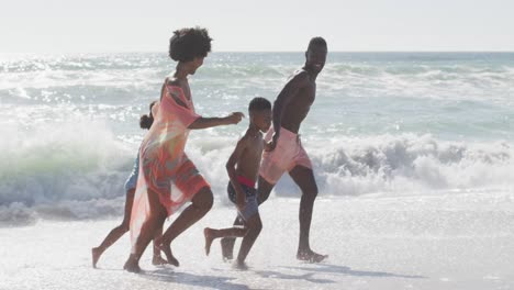 Familia-Afroamericana-Sonriente-Tomándose-De-La-Mano-Y-Corriendo-En-La-Playa-Soleada