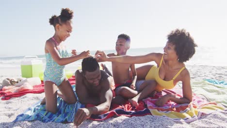 Lächelnde-Afroamerikanische-Familie,-Die-Auf-Handtüchern-Am-Sonnigen-Strand-Liegt