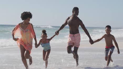 Familia-Afroamericana-Sonriente-Tomándose-De-La-Mano-Y-Corriendo-En-La-Playa-Soleada
