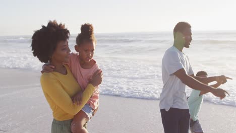 Lächelnde-Afroamerikanische-Familie,-Die-Am-Sonnigen-Strand-Spaziert-Und-Zeigt
