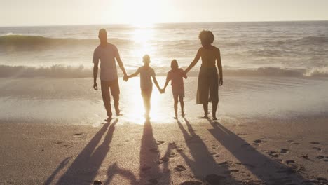 Lächelnde-Afroamerikanische-Familie,-Die-Am-Sonnigen-Strand-Händchen-Hält