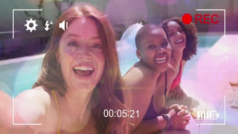 Animation-of-video-over-happy-diverse-female-friends-in-pool-taking-self-movie