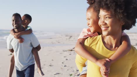Familia-Afroamericana-Sonriente-Abrazando-Y-Caminando-En-La-Playa-Soleada