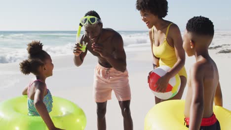 Lächelnde-Afroamerikanische-Familie-Mit-Schlauchbooten-Im-Gespräch-Am-Sonnigen-Strand