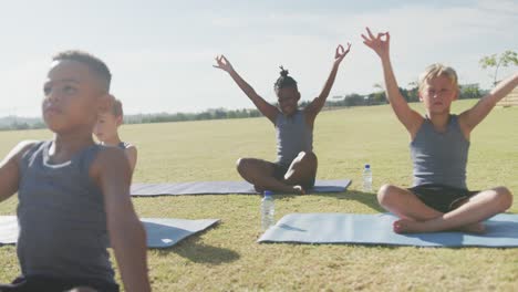 Video-of-diverse-boys-practicing-yoga-on-mats-on-sunny-day