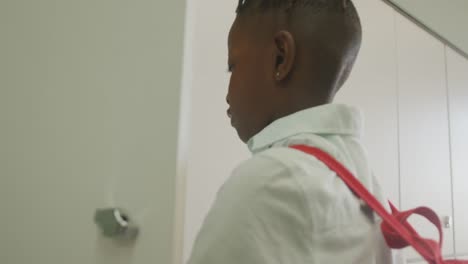 Video-of-african-american-boy-closing-locker-and-smiling-at-school