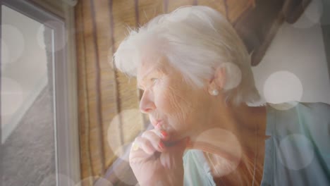 Animation-of-glowing-lights-over-a-sad-caucasian-senior-woman