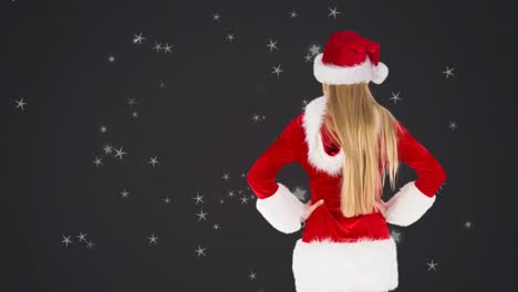 Animation-of-stars-over-back-of-caucasian-woman-in-santa-hat-on-black-background