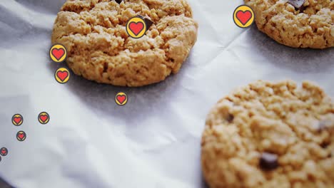 Animation-of-hearts-floating-over-cookies-on-cooking-paper