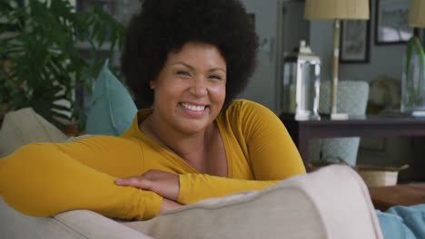 Video-of-happy-plus-size-african-american-woman-sitting-on-sofa