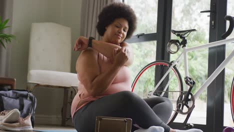 Video-of-midsection-of-plus-size-african-american-woman-in-sport-clothes-stretching-at-home