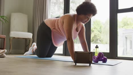 Video-of-midsection-of-plus-size-african-american-woman-exercising-with-online-lessons-at-home