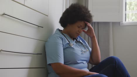 Video-of-tired-plus-size-african-american-female-doctor-resting-at-social-room