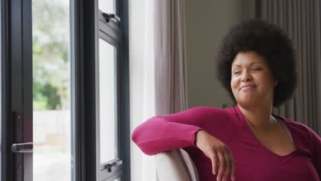 Video-Einer-Glücklichen-Afroamerikanischen-Frau-In-Übergröße,-Die-Aus-Dem-Fenster-Schaut