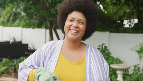 Video-Einer-Glücklichen-Afroamerikanerin-In-Übergröße,-Die-Blumen-Im-Garten-Gießt