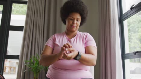 Video-Einer-Afroamerikanischen-Frau-In-Übergröße-In-Sportkleidung,-Die-Eine-Smartwatch-Anzieht
