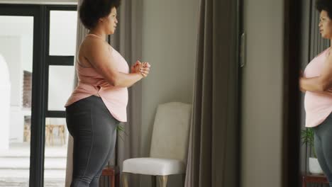 Video-of-plus-size-african-american-woman-exercising-at-home,-doing-squats