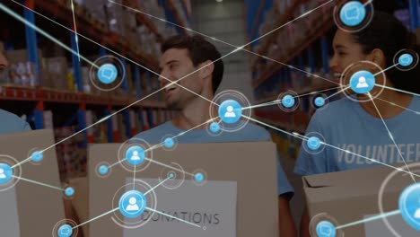 Animation-of-network-of-connected-people-icons-over-diverse-volunteers-in-warehouse