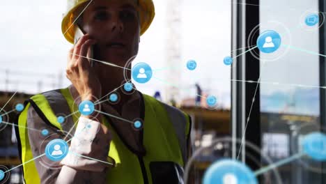 Animation-of-network-of-people-icons-over-caucasian-woman-in-high-vis-vest-talking-on-smartphone