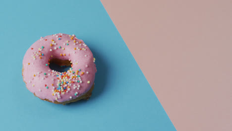 Video-Von-Donut-Mit-Zuckerguss-Auf-Blauem-Und-Rosa-Hintergrund