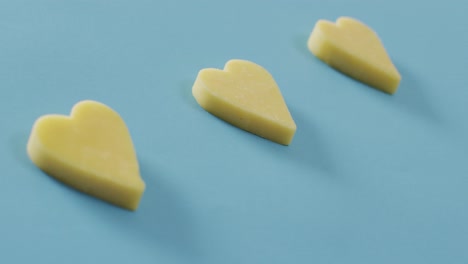Video-of-row-of-heart-shapes-of-cheese-on-blue-background-with-copy-space