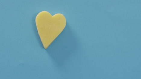 Video-of-heart-shape-of-cheese-on-blue-background-with-copy-space