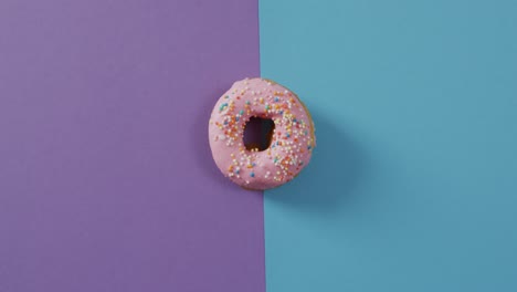 Video-Von-Donut-Mit-Zuckerguss-Auf-Violettem-Und-Blauem-Hintergrund