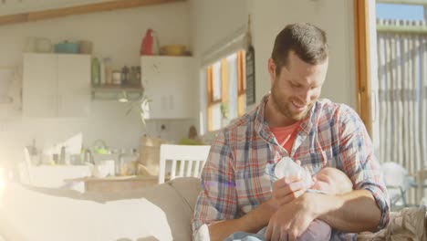 Animation-of-light-spots-over-happy-caucasian-father-feeding-baby-at-home