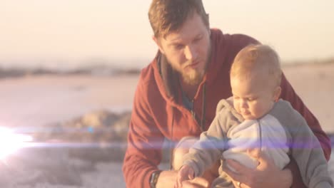 Animation-of-light-spots-over-caucasian-father-holding-child-at-beach