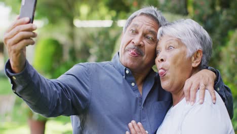 Video-Eines-Glücklichen-Gemischtrassigen-älteren-Paares,-Das-Sich-Im-Garten-Umarmt-Und-Ein-Selfie-Macht