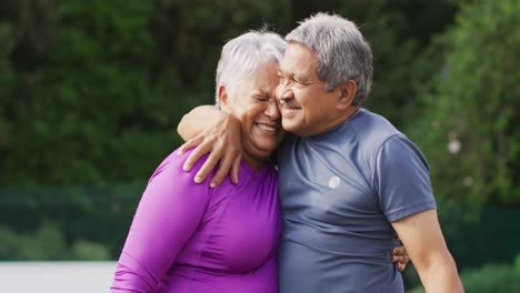 Vídeo-De-Una-Feliz-Pareja-Birracial-De-Ancianos-Abrazándose-Durante-El-Entrenamiento-En-La-Cancha-De-Tenis