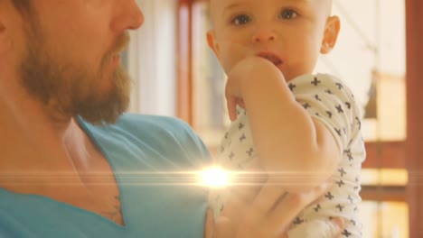 Animation-of-lights-over-happy-caucasian-father-holding-baby-son