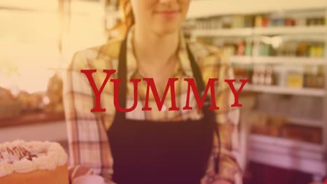 Animation-of-yummy-text-over-smiling-caucasian-female-worker-in-baker