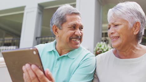 Video-Eines-Glücklichen-Gemischtrassigen-älteren-Paares,-Das-Im-Garten-Ein-Tablet-Benutzt