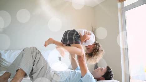 Animation-of-bokeh-over-happy-caucasian-father-and-son-having-fun-at-home