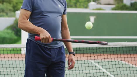 Video-Des-Mittelteils-Eines-Gemischtrassigen-älteren-Mannes,-Der-Einen-Schläger-Hält-Und-Einen-Ball-Auf-Dem-Tennisplatz-Wirft