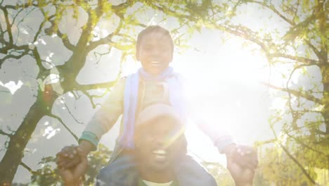 Animation-of-foliage-over-happy-african-american-father-and-son-having-fun-outdoors