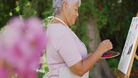 Video-of-happy-biracial-senior-woman-painting-in-garden
