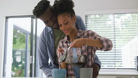 Video-Eines-Glücklichen-Afroamerikanischen-Paares,-Das-Zu-Hause-Kaffee-Zubereitet-Und-Sich-Umarmt