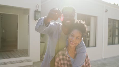 Video-Eines-Glücklichen-Afroamerikanischen-Paares,-Das-Sich-Umarmt-Und-Die-Schlüssel-Zum-Neuen-Haus-Zeigt